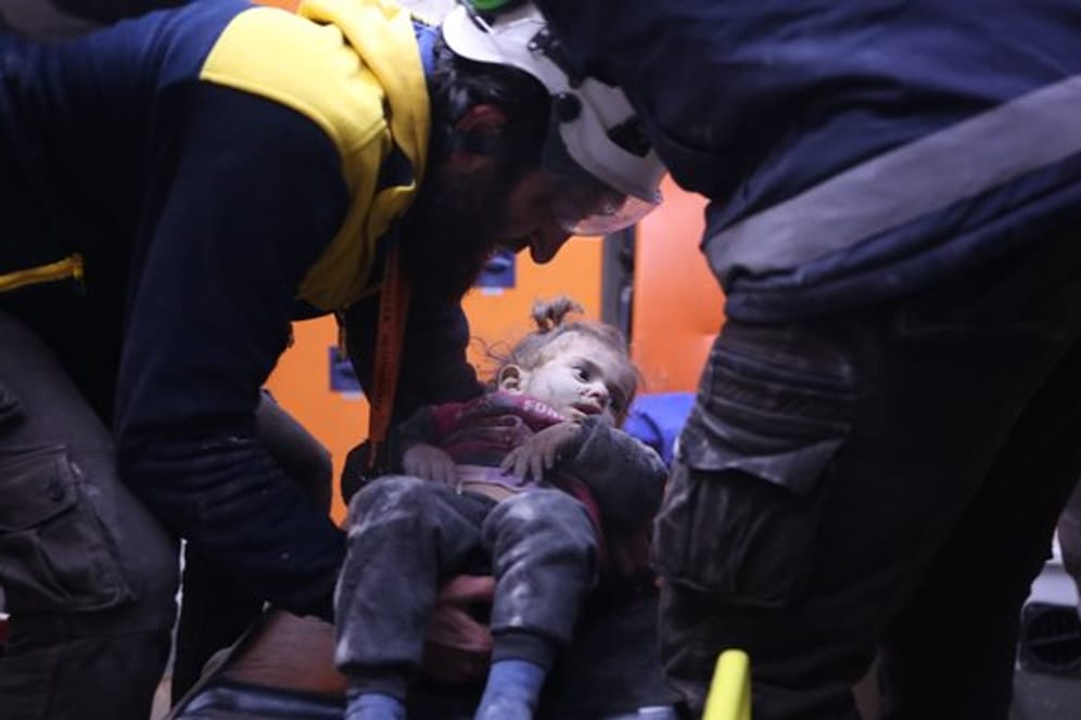 Rettungskräfte versorgen nach einem Luftangriff ein verwundetes Mädchen.
