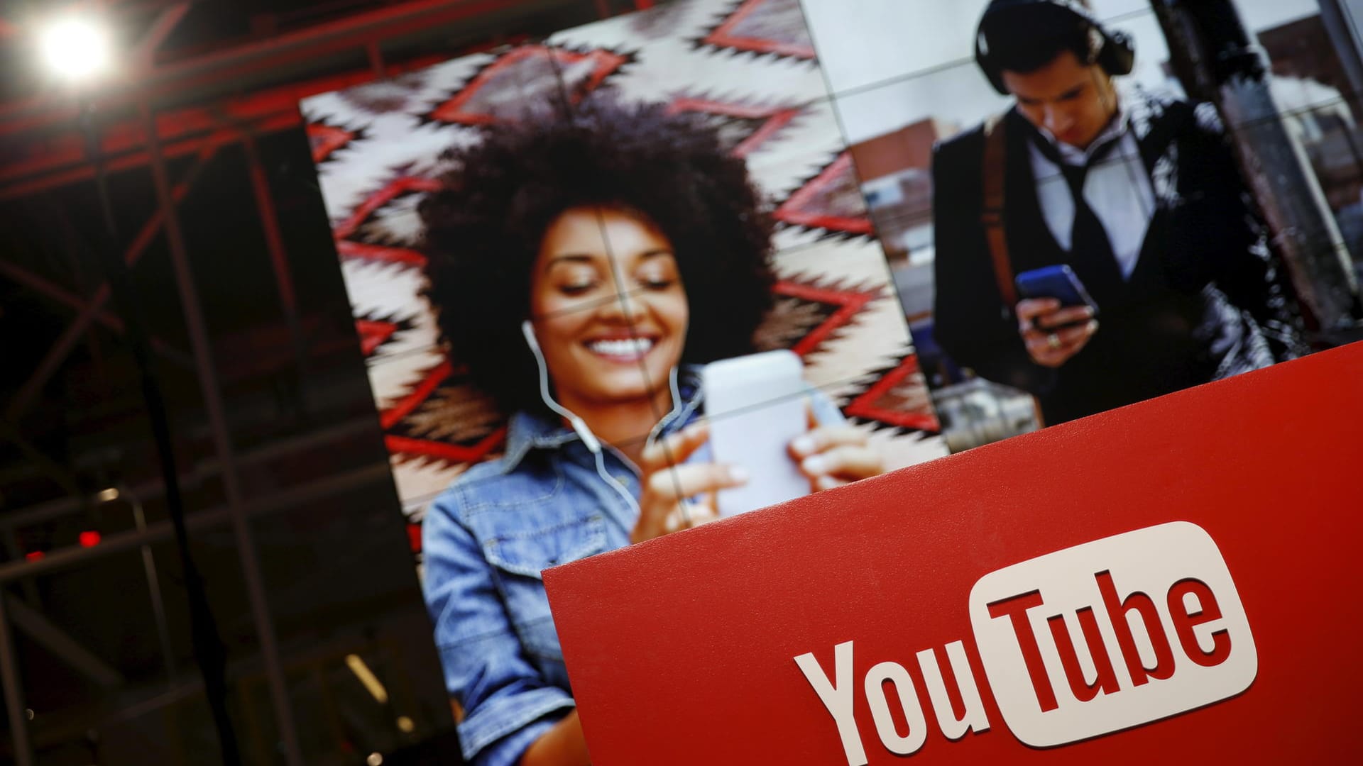 YouTube-Logo und im Hintergrund Fotos von Menschen, die auf ein Smartphone schauen: Die Mehrheit der YouTube-User schaut die Videos auf dem Smartphones.