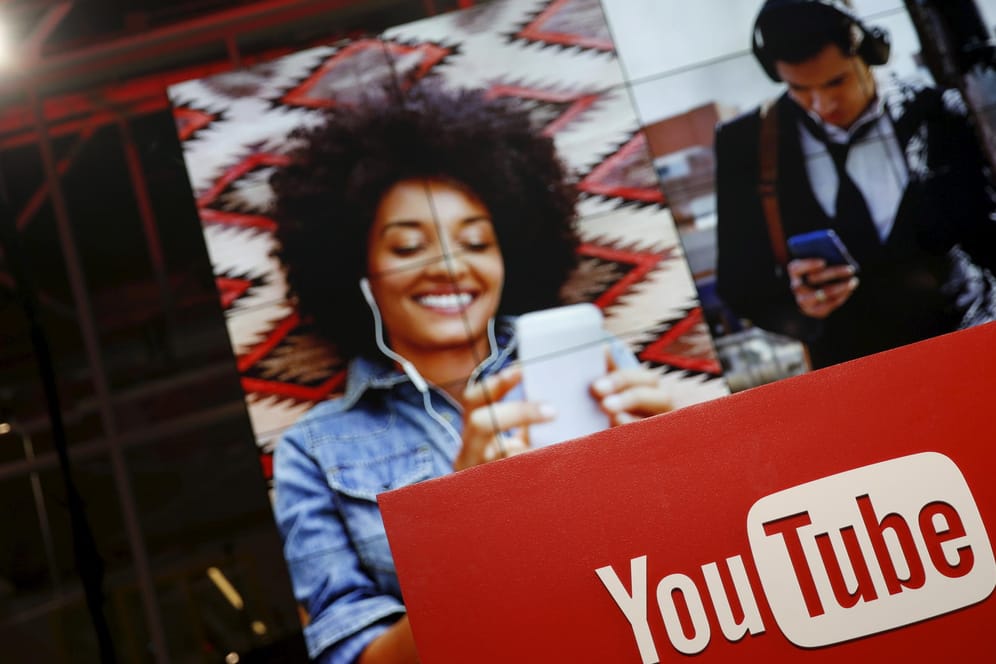 YouTube-Logo und im Hintergrund Fotos von Menschen, die auf ein Smartphone schauen: Die Mehrheit der YouTube-User schaut die Videos auf dem Smartphones.