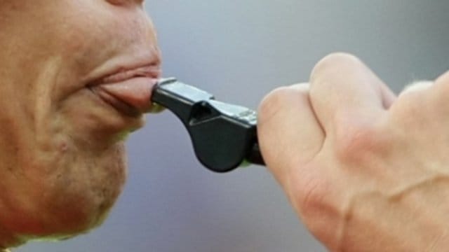 Ein Schiedsrichter setzt zu einem Pfiff an.