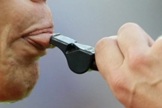 Ein Schiedsrichter setzt zu einem Pfiff an.