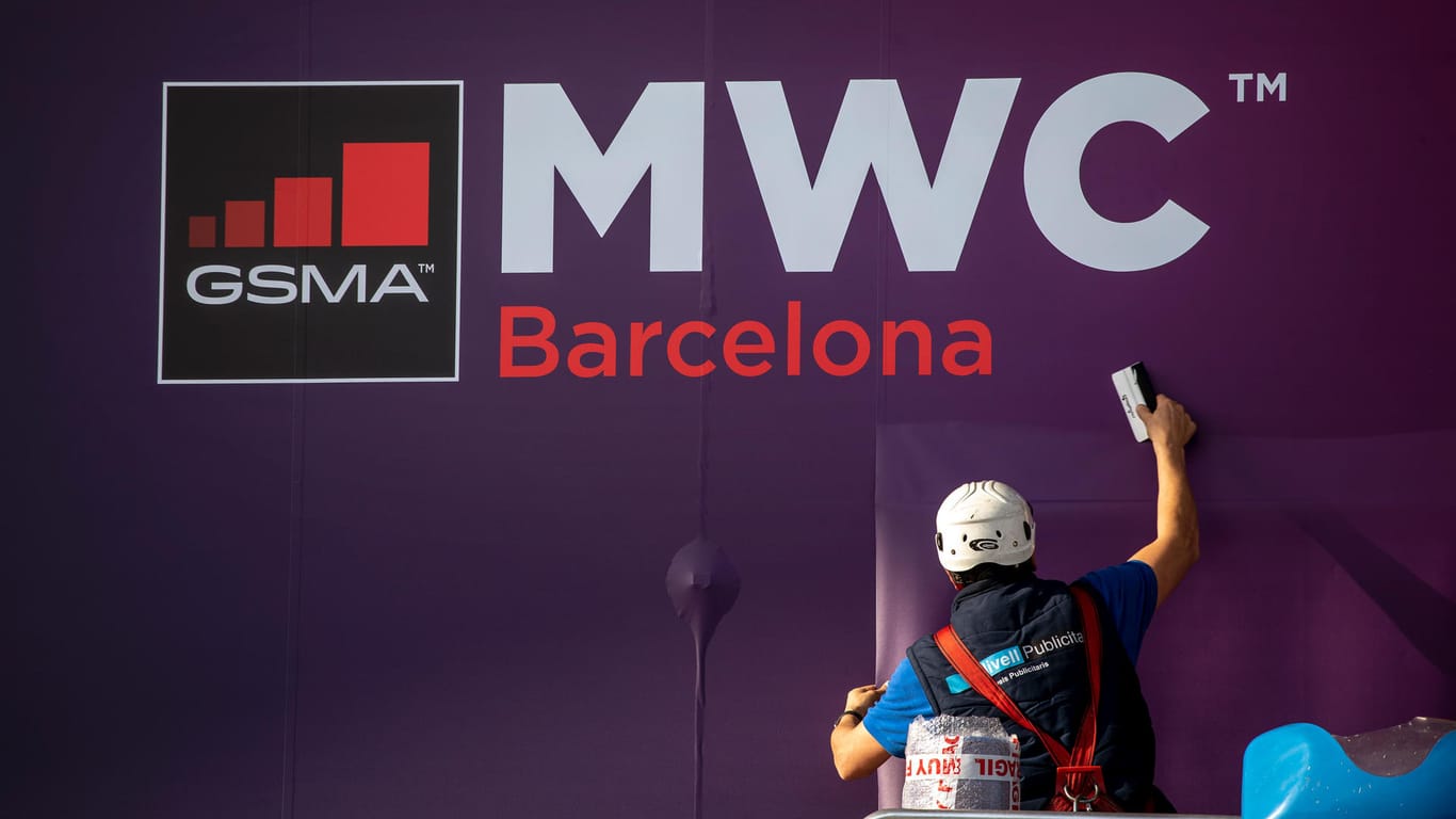 Ein Arbeiter klebt ein Poster zur Ankündigung der weltgrößten Mobilfunkmesse MWC in Barcelona: Jetzt wurde die Messe wegen des Coronavirus abgesagt.