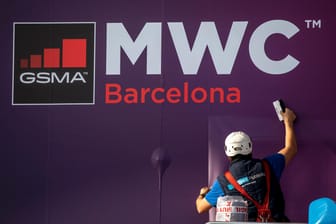Ein Arbeiter klebt ein Poster zur Ankündigung der weltgrößten Mobilfunkmesse MWC in Barcelona: Jetzt wurde die Messe wegen des Coronavirus abgesagt.