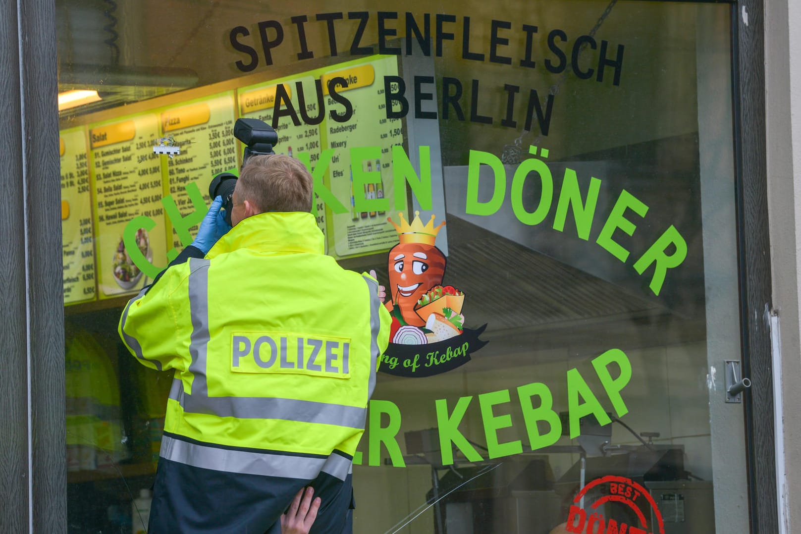 Ein Kriminaltechniker fotografiert das neue Loch: Beim Döner-Imbiss ist nach dem Terroranschlag in Halle der Umsatz eingebrochen.