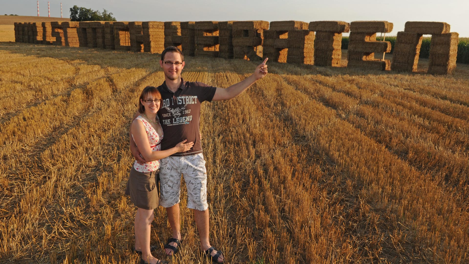 Heiratsantrag mit Strohballen: Markus Schmidt und Corinna Pesl stehen vor den aus Strohballen errichteten Worten "Willst mich heiraten". Schmidt baute den ungewöhnlichen Heiratsantrag für seine Freundin aus 152 Strohballen. Heiratsantrag mit Strohballen: Markus Schmidt und Corinna Pesl stehen vor den aus Strohballen errichteten Worten "Willst mich heiraten". Schmidt baute den ungewöhnlichen Heiratsantrag für seine Freundin aus 152 Strohballen.