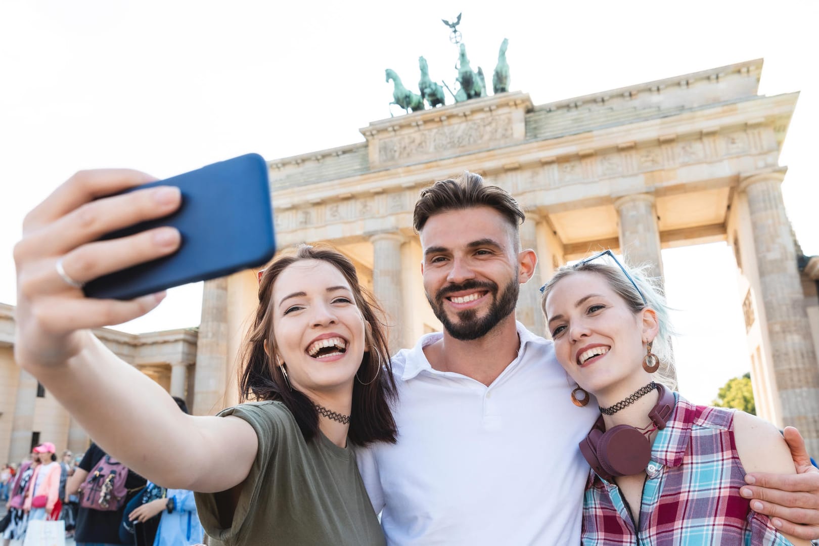 Vor dem Brandenburger Tor in Berlin: Selfie-Portrait dreier junger Menschen.