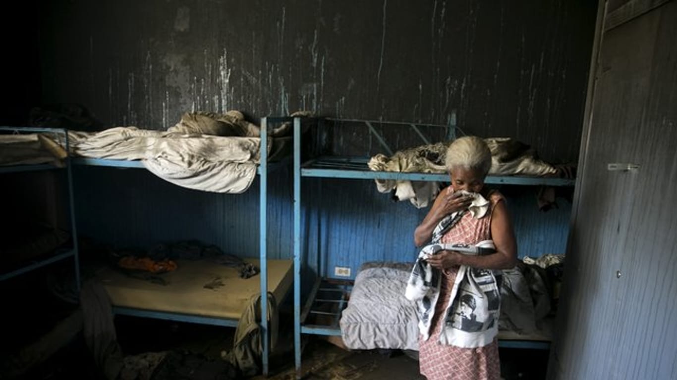 Eine Mitarbeiterin des von Flammen verwüsteten Waisenhauses steht in einem Schlafzimmer.