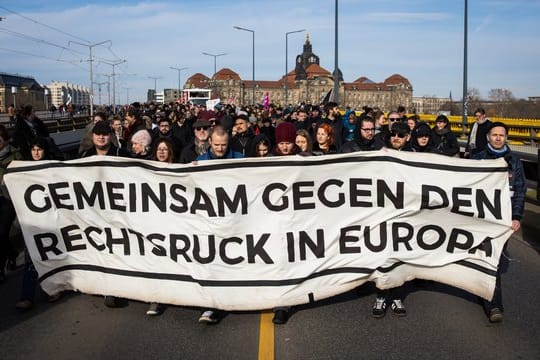 Gegendemonstranten ziehen mit einem Banner durch Dresden.