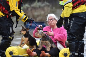 Rettungskräfte bringen eine Frau und ihre zwei Hunde per Schlauchboot in Sicherheit: In England sorgt Sturm "Dennis" für Chaos.