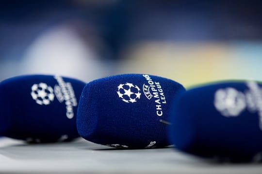 Mikrofone mit dem Logo der Champions League liegen vor einem Spiel auf einem Tisch.
