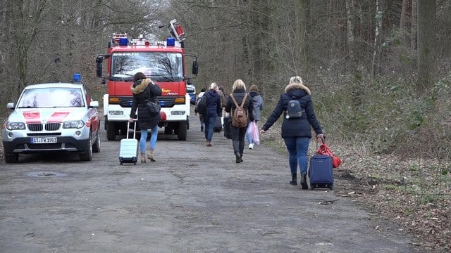 Bahnreisende ziehen ihre Rollkoffer über eine Straße bei Rheine.