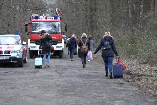 Bahnreisende ziehen ihre Rollkoffer über eine Straße bei Rheine.