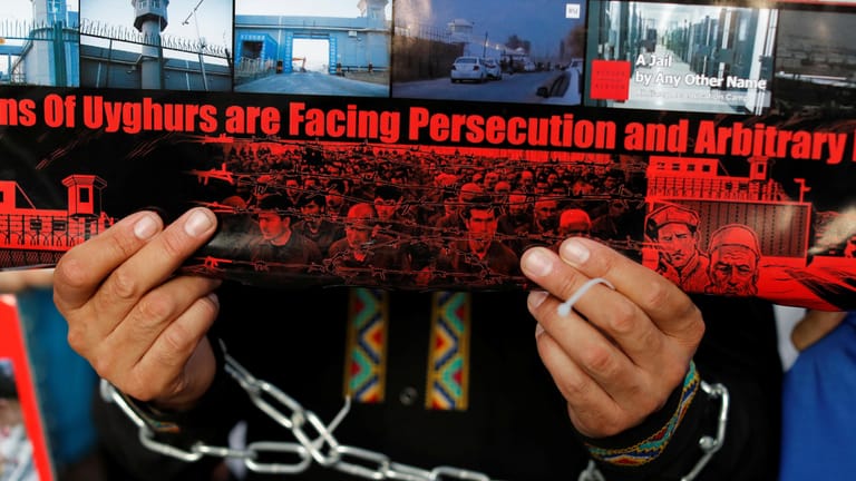 Ein Uigure hält ein Plakat hoch: Die chinesische Regierung bezeichnet Gefangenenlager als "Berufsbildungszentren".