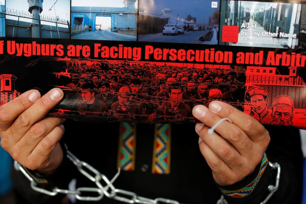 Ein Uigure hält ein Plakat hoch: Die chinesische Regierung bezeichnet Gefangenenlager als "Berufsbildungszentren".