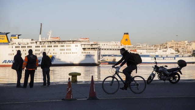 Passanten stehen vor den angedockten Fähren im Hafen von Piräus. Passanten stehen vor den angedockten Fähren im Hafen von Piräus.