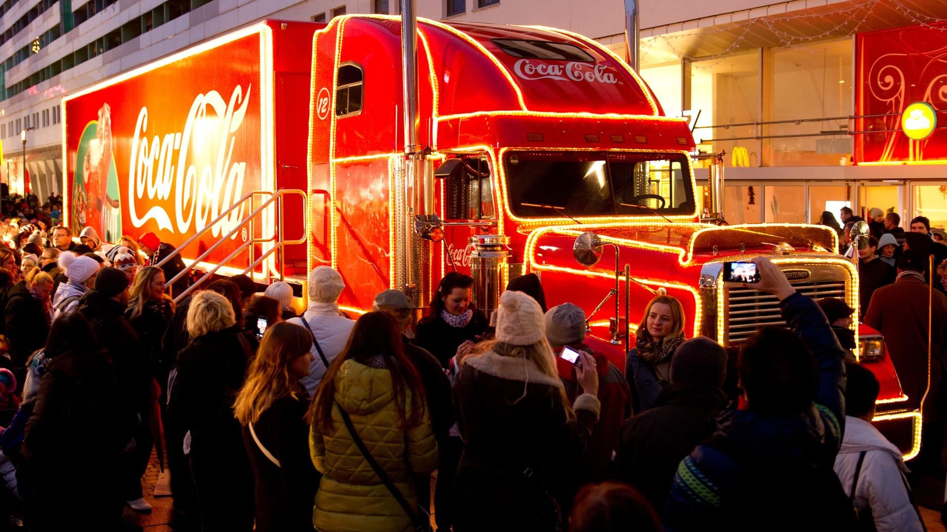 Menschen stehen vor dem Coca-Cola Weihnachtstruck: Minderjährige in reichen Ländern haben es besser als Altersgenossen in armen Ländern.