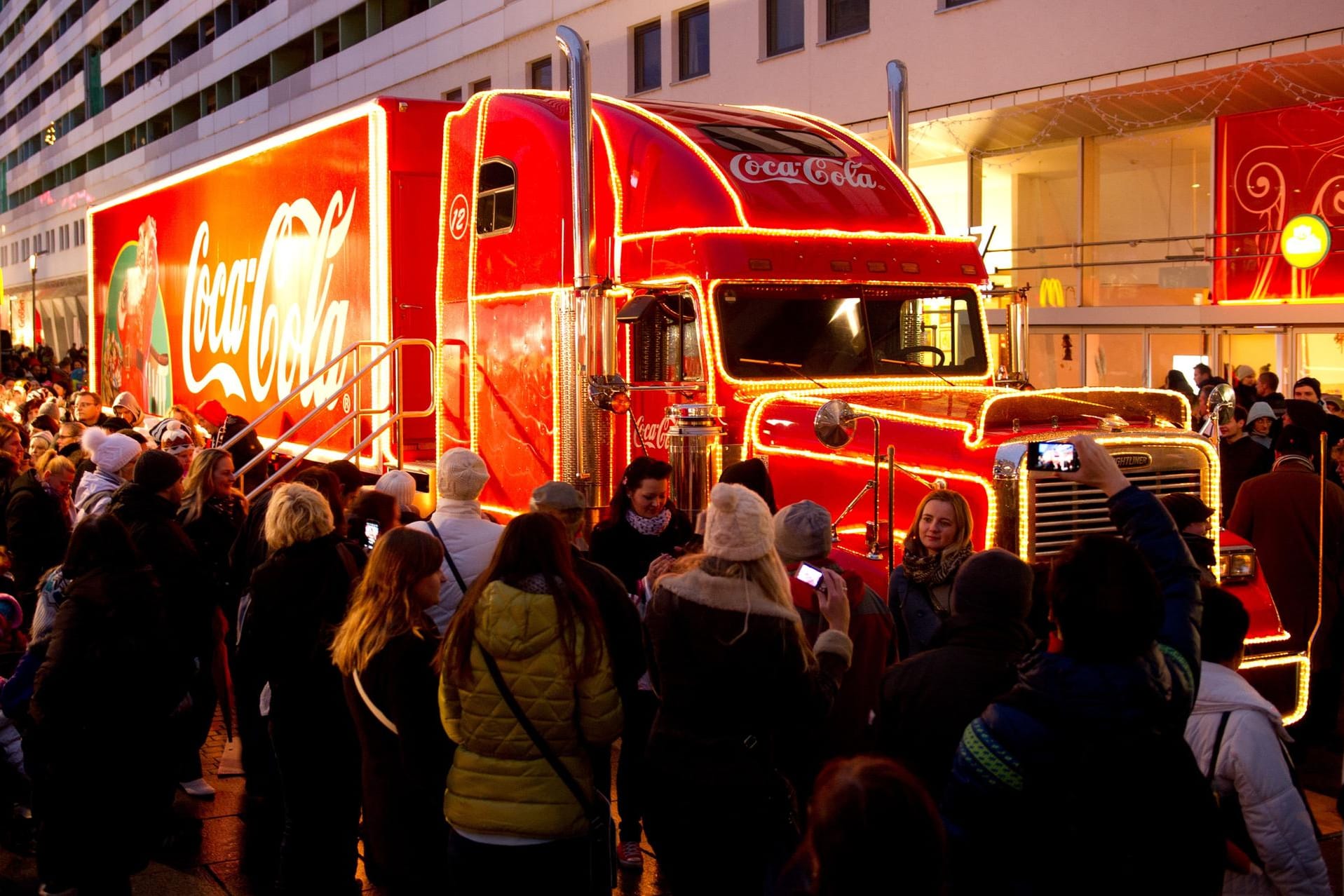 Menschen stehen vor dem Coca-Cola Weihnachtstruck: Minderjährige in reichen Ländern haben es besser als Altersgenossen in armen Ländern.