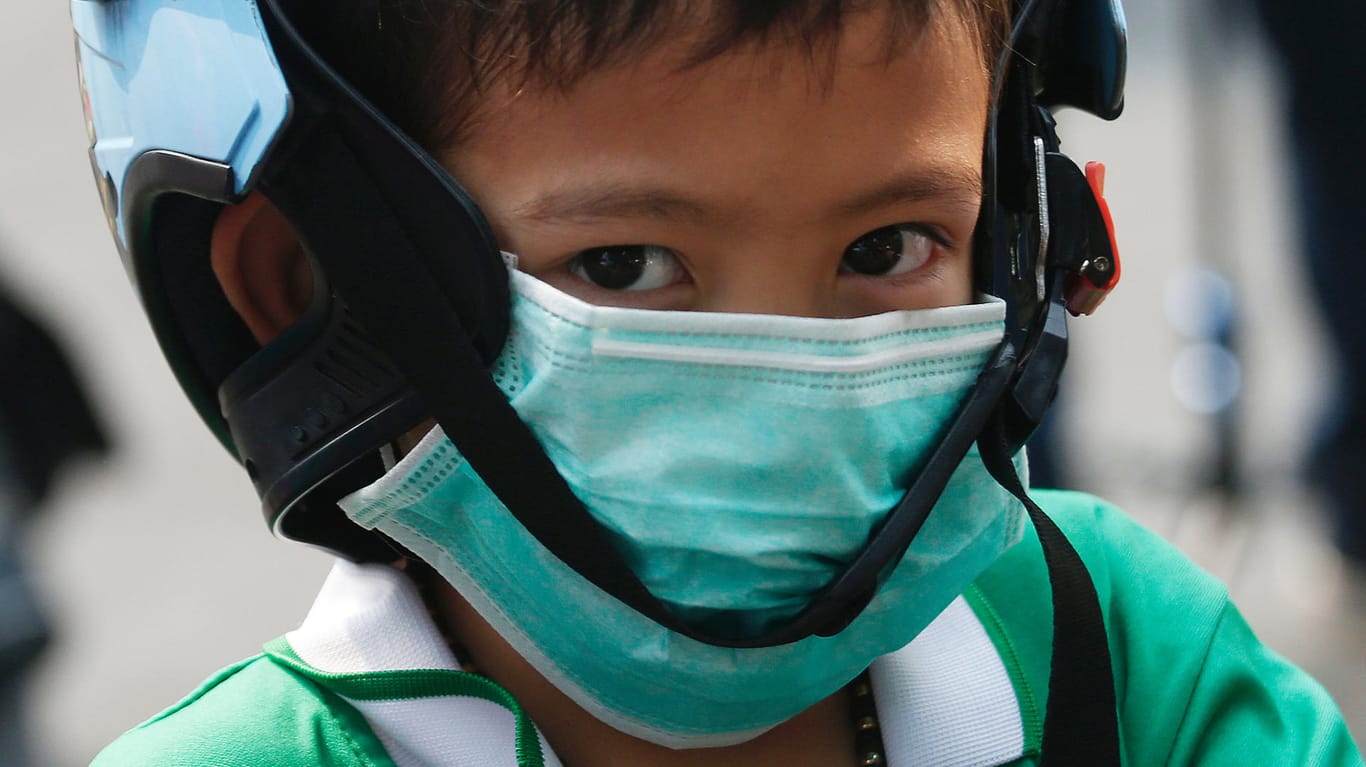 Thailand, Bangok: Ein Schüler trägt eine Schutzmaske wegen der hohen Luftverschmutzung während er die Schule verlässt.