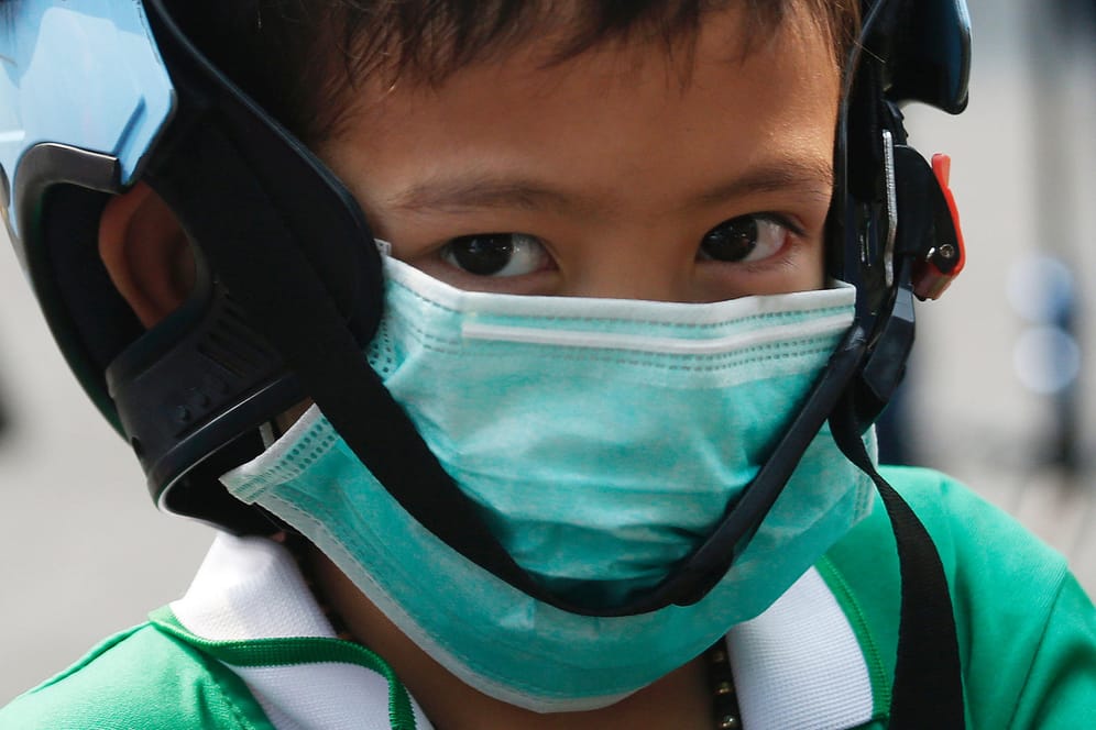 Thailand, Bangok: Ein Schüler trägt eine Schutzmaske wegen der hohen Luftverschmutzung während er die Schule verlässt.