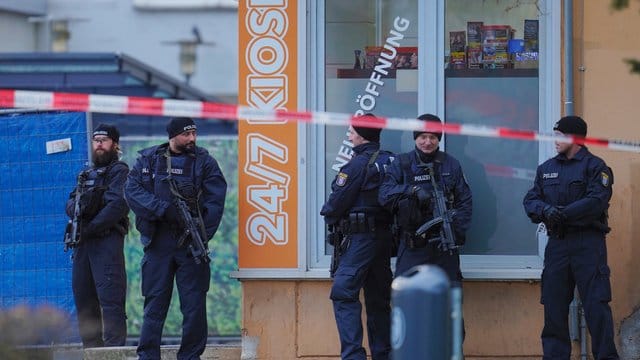 Mit Maschinenpistolen bewaffnete Einsatzkräfte der Polizei vor einem Kiosk am Tatort in Hanau-Kesselstadt. Mit Maschinenpistolen bewaffnete Einsatzkräfte der Polizei vor einem Kiosk am Tatort in Hanau-Kesselstadt.