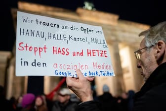 Ein Mann hält ein Plakat hoch: Menschen kamen zur Mahnwache am Brandenburger Tor zusammen.