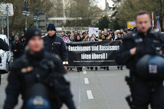 Zahlreiche Menschen laufen in Hanau während eines Trauermarsches vom Tatort Heumarkt zum Tatort Kurt-Schumacher-Platz.