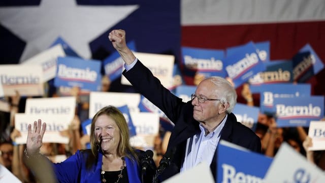 Bernie Sanders und seine Frau Jane stehen bei einer Wahlkampfveranstaltung inmitten von Anhängern. Bernie Sanders und seine Frau Jane stehen bei einer Wahlkampfveranstaltung inmitten von Anhängern.