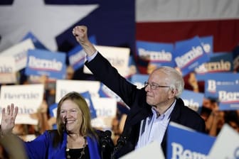 Bernie Sanders und seine Frau Jane stehen bei einer Wahlkampfveranstaltung inmitten von Anhängern.