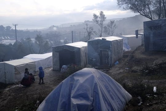 Kinder stehen nach einem Regenguss vor provisorisch errichteten Zelten außerhalb des Flüchtlingslagers Moria auf Lesbos.