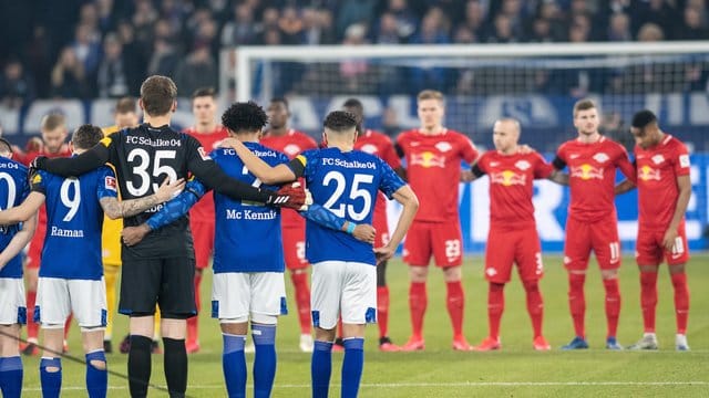 Die Teams von Schalkes und Leipzig nehmen an einer Gedenkminute teil. Die Teams von Schalkes und Leipzig nehmen an einer Gedenkminute teil.