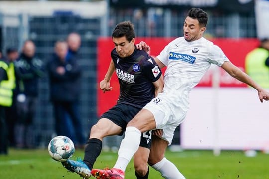 Karlsruhes Dirk Carlson (l) und Sandhausens Aziz Bouhaddouz kämpfen um den Ball.