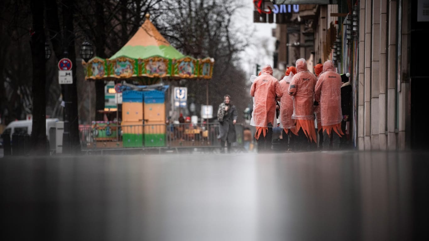Karnevalisten stehen im Regen an der Kö: Das närrische Kö-Treiben in Düsseldorf wurde wegen stürmischem Wetter abgesagt.