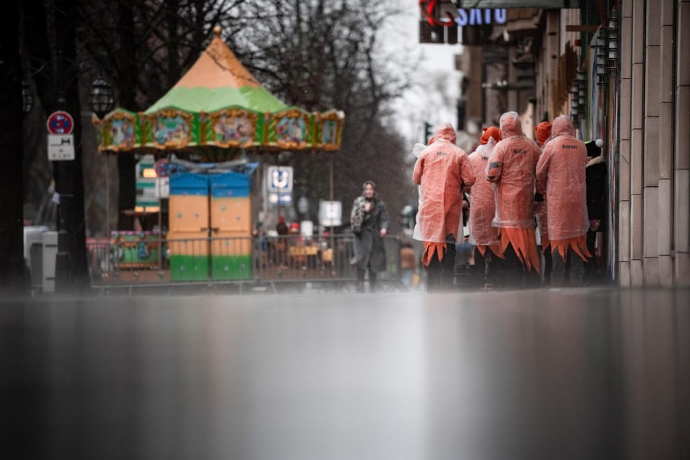 Karnevalisten stehen im Regen an der Kö: Das närrische Kö-Treiben in Düsseldorf wurde wegen stürmischem Wetter abgesagt.