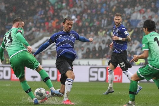 Die Spieler von Arminia Bielefeld und Hannover 96 kämpfen in der Schüco-Arena auf durchweichtem Rasen um den Ball.