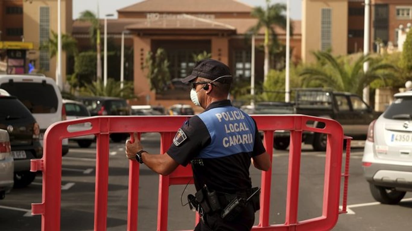 Ein Polizist setzt eine Sperre, die den Zugang zum Hotel H10 Costa Adeje Palace auf Teneriffa blockiert.