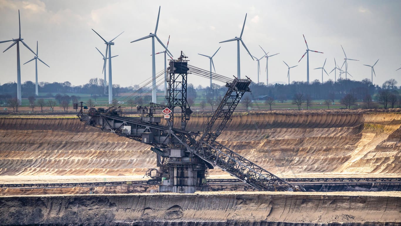 Der Braunkohletagebau im Garzweiler (Nordrhein-Westfalen) steht im Kontrast zu den Windkraftanlagen. Deutsche Konzerne investieren laut einer neuen Studie mehr in erneuerbare Energien.