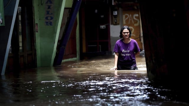 Eine Frau watet durch das Hochwasser einer überschwemmten Straße in Jakarta.