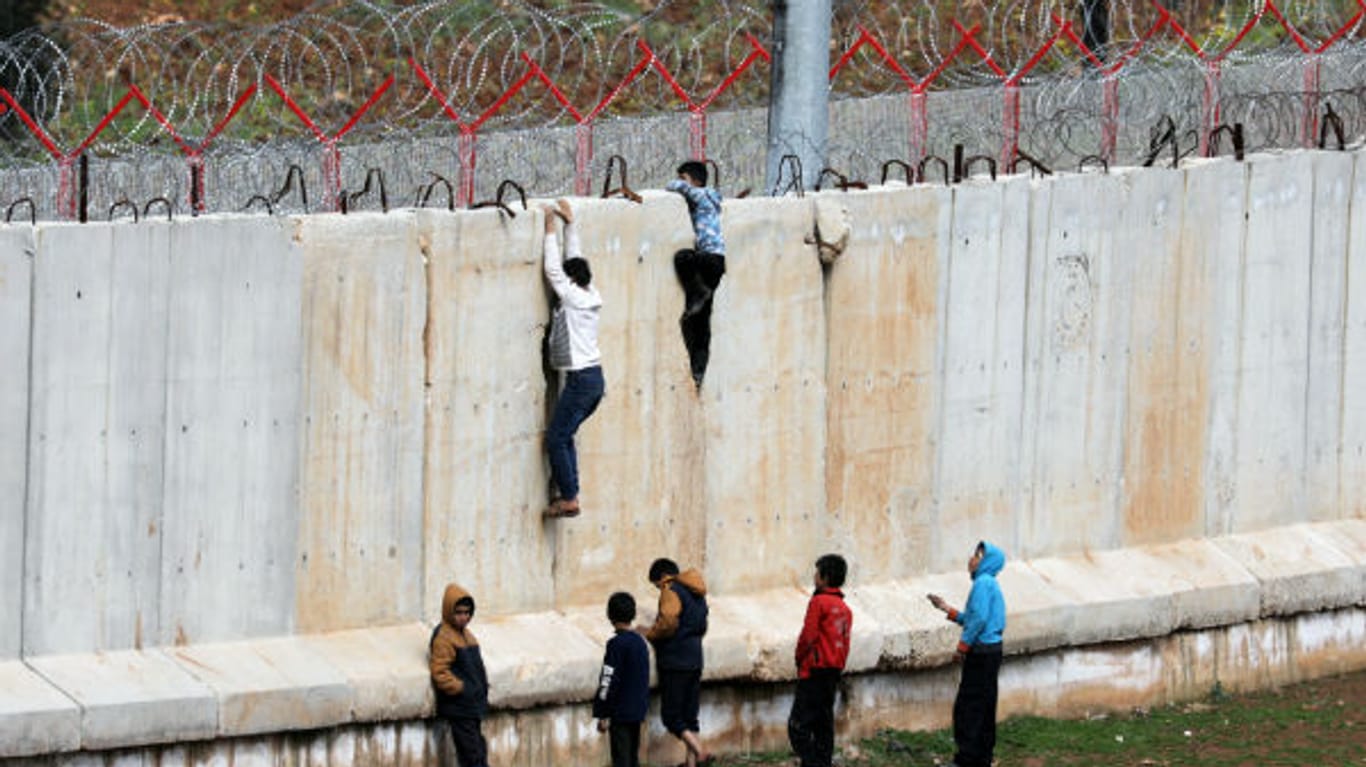 Jungs versuchen, über die Mauer an der Grenze zur Türkei zu klettern.
