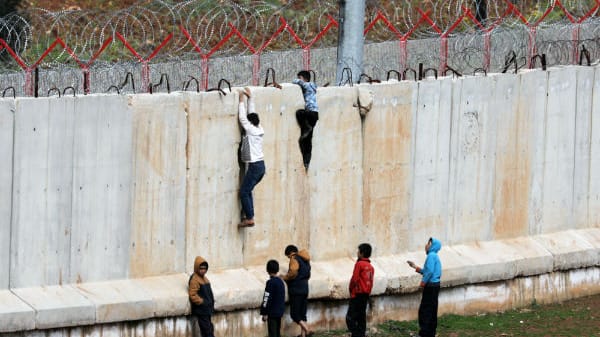 Jungs versuchen, über die Mauer an der Grenze zur Türkei zu klettern.