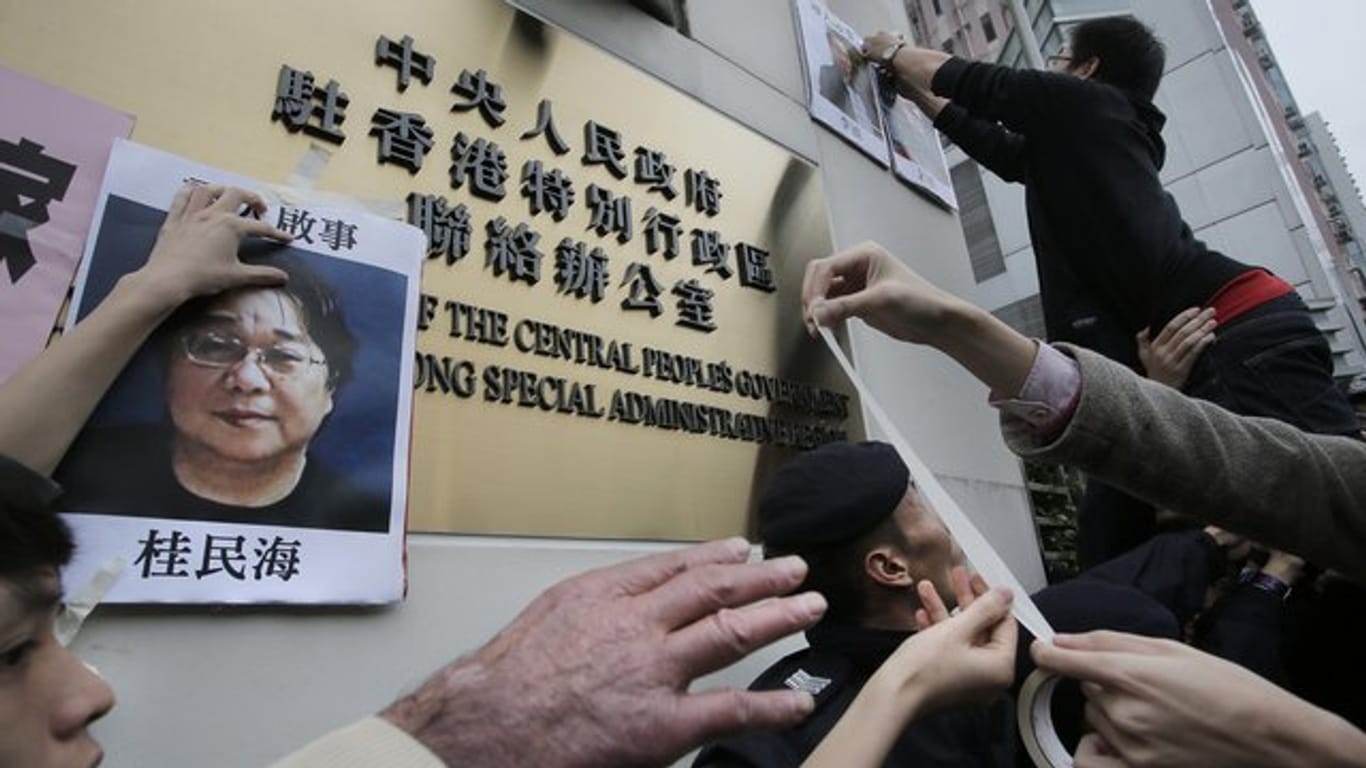 Demonstranten versuchen bei einer Kundgebung ein Foto des Hongkonger Buchhändlers Gui Minhai aus Protest gegen seine Verhaftung am Regierungssitz zu befestigen.