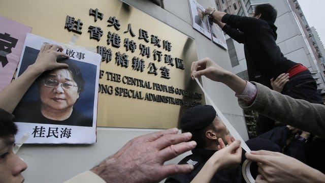 Demonstranten versuchen bei einer Kundgebung ein Foto des Hongkonger Buchhändlers Gui Minhai aus Protest gegen seine Verhaftung am Regierungssitz zu befestigen. Demonstranten versuchen bei einer Kundgebung ein Foto des Hongkonger Buchhändlers Gui Minhai aus Protest gegen seine Verhaftung am Regierungssitz zu befestigen.