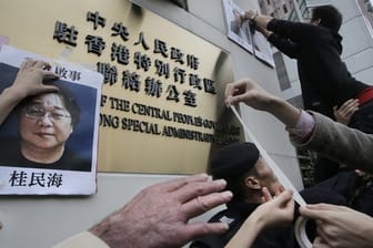 Demonstranten versuchen bei einer Kundgebung ein Foto des Hongkonger Buchhändlers Gui Minhai aus Protest gegen seine Verhaftung am Regierungssitz zu befestigen.