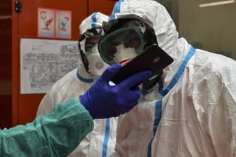Kommunikation von Helfern in Schutzanzügen: In Italien ist die Zahl der Coronavirus-Toten und -Infizierten weiter gestiegen.