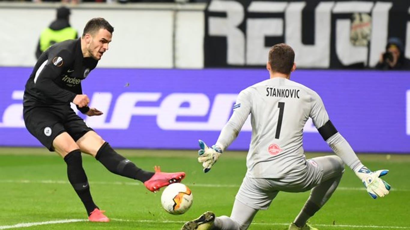 Eintracht hat ein gutes Polster für das Rückspiel in Salzburg: Frankfurts Filip Kostic (l) erzielt das Tor zum 4:0 gegen Salzburgs Torhüter Cican Stankovic.