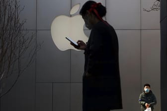 Mann mit Maske vor einem Apple-Logo: Der Corona-Ausbruch könnte den Zeitplan für das neue iPhone im Herbst gefährden
