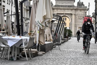 Ein Fahrradbote mit Mundschutz in Mailand: Die Region in Norditalien, in der Gosens spielt, ist vom Coronavirus-Ausbruch besonders betroffen.
