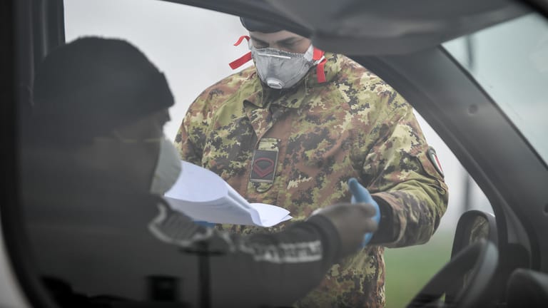 Ein Soldat kontrolliert an einer Straßensperre am Rand des abgesperrten Ortes Turano Lodigiano einen Autofahrer: Die internationale Presse zeigt sich angesichts der rasanten Ausbreitung des Coronavirus besorgt.