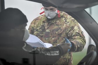 Ein Soldat kontrolliert an einer Straßensperre am Rand des abgesperrten Ortes Turano Lodigiano einen Autofahrer: Die internationale Presse zeigt sich angesichts der rasanten Ausbreitung des Coronavirus besorgt.