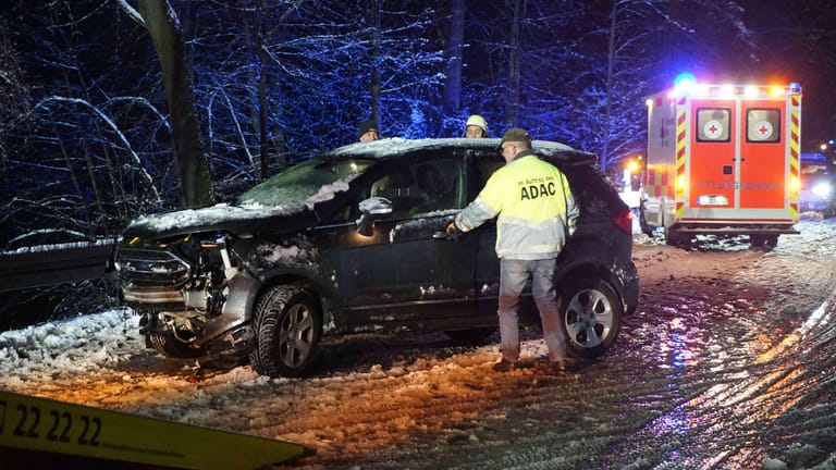 Bayern: Nach einem Unfall auf einer schneebedeckten Straße bei Burglengenfeld im Landkreis Schwandorf kümmern sich Helfer um ein Fahrzeug.