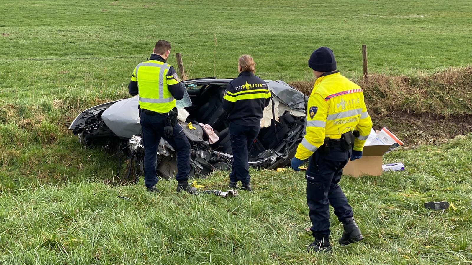 Polizisten am Fahrzeugwrack: Von der Unfallstelle soll eine Person weggelaufen sein, zwei weitere Insassen kamen bei dem Unfall ums Leben. Polizisten am Fahrzeugwrack: Von der Unfallstelle soll eine Person weggelaufen sein, zwei weitere Insassen kamen bei dem Unfall ums Leben.